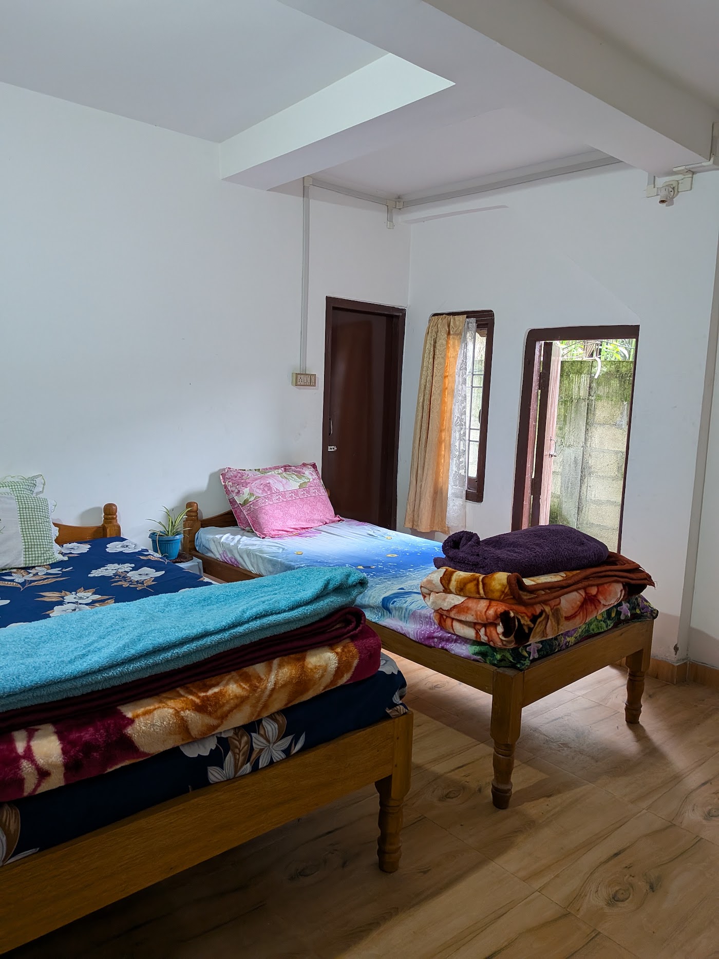 Two wooden single beds under a skylight, with folded blankets
